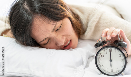 Cuadro en lienzo Asian girl is sleeping comfortably on the bed in her bedroom, shocked by the sound of the alarm clock in the morning