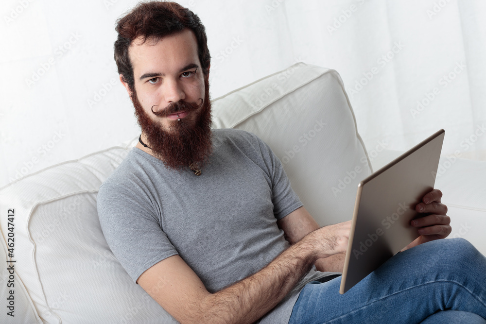 hipster dude on a sofa with a tablet hipster dude on a sofa with a tablet