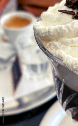 Close-up of a glass Irish Coffee with an espresso cup and white china in the background