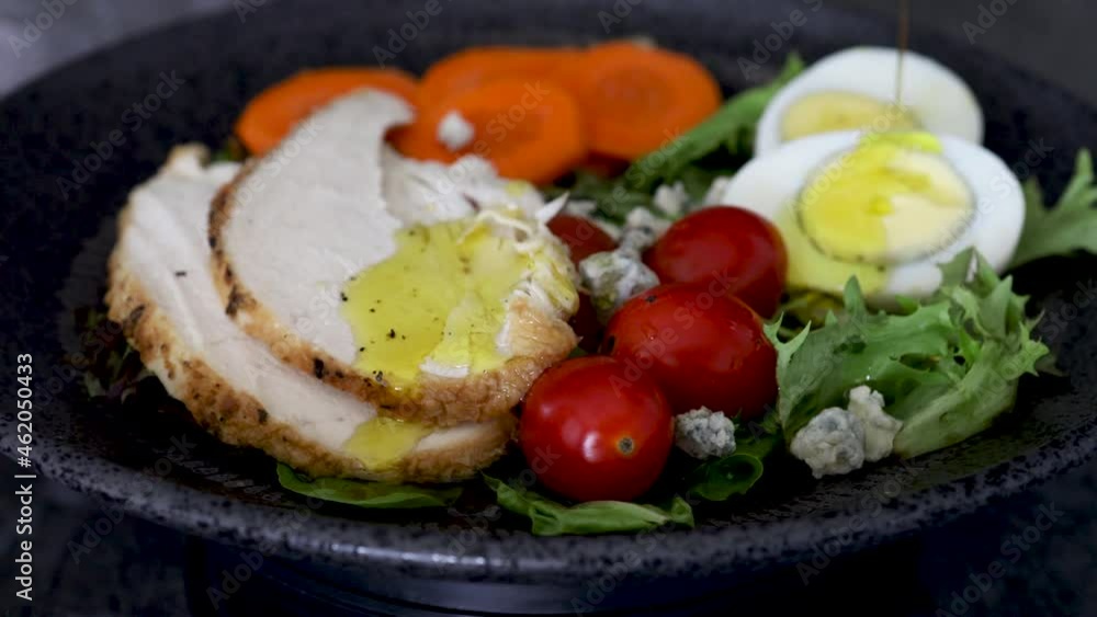 Pouring Salad Dressing over a Salad with Chicken, Tomatoes and Eggs Pouring Salad Dressing over a Salad with Chicken, Tomatoes and Eggs
