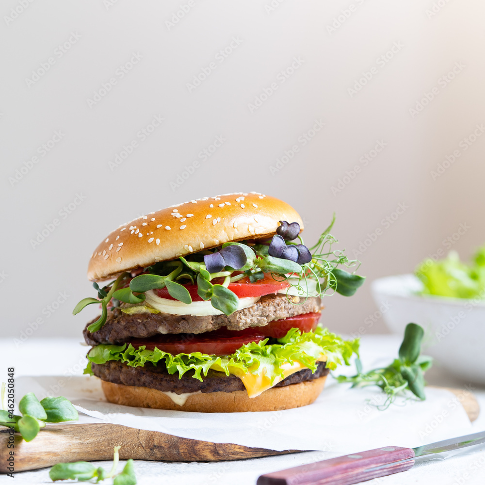 Double cheeseburger with veal cutlets, tomatoes, lettuce leaves and cucumbers. Fast food. Double cheeseburger with veal cutlets, tomatoes, lettuce leaves and cucumbers. Fast food.