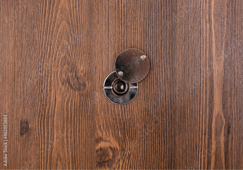 opening door peephole with a lens on a dark wooden texture