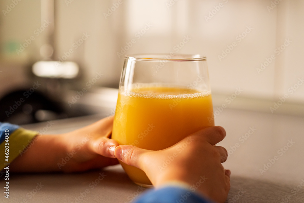 Child's hands grabbing a crystal glass with orange juice on the kitchen counter. Child's hands grabbing a crystal glass with orange juice on the kitchen counter.