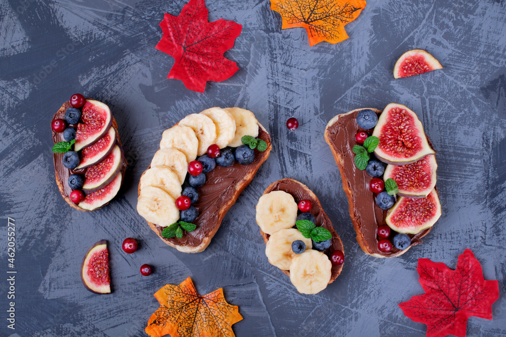 Sweet sandwiches assortment with chocolate nut butter, fig, blueberry, banana and cranberry on the gray table. Top view