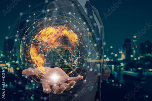 Double exposure of Businessman hand holding the particle earth with technology network circle over the photo blurred of cityscape background, technology and innovation concept