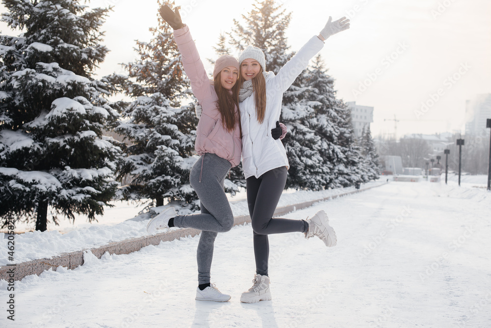 Two young athletic girls walking and playing sports on a sunny winter day. A healthy way of life. Two young athletic girls walking and playing sports on a sunny winter day. A healthy way of life.