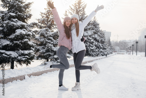Two young athletic girls walking and playing sports on a sunny winter day. A healthy way of life.