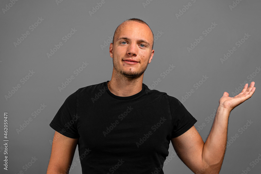 Smiling young presenting something in his palm against a gray background Smiling young presenting something in his palm against a gray background