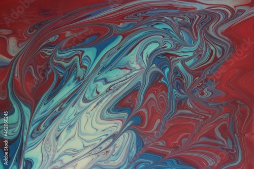 Abstract background of blue and red marble. Acrylic paint mixes freely and creates an interesting pattern. Bright saturated shades. Background for the cover of a laptop, laptop.