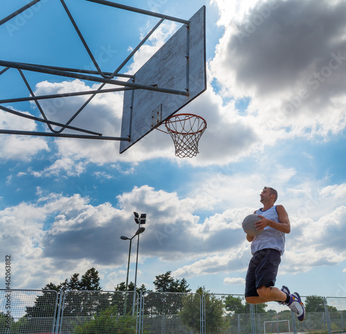Basketball player jumping to the hoop in an outdoor court