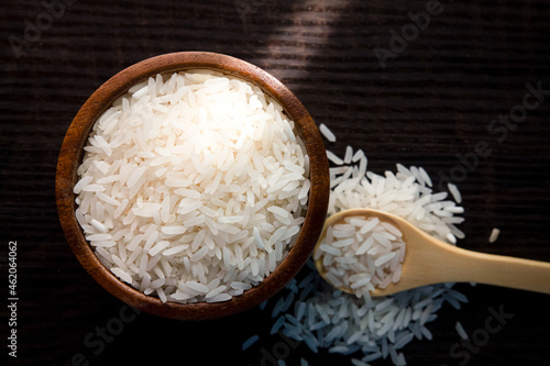 Top view of white rice in wooden bowl on dark wooden table