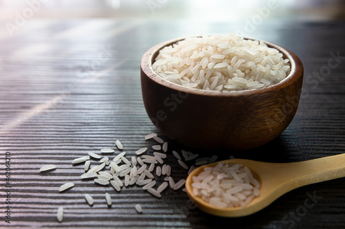 White rice in wooden bowl on dark wooden table.