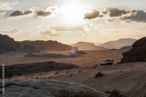 evening in the desert of Wadi Rum  contrasting shadows from the mountains  a white car rides in the desert  nature of Jordan