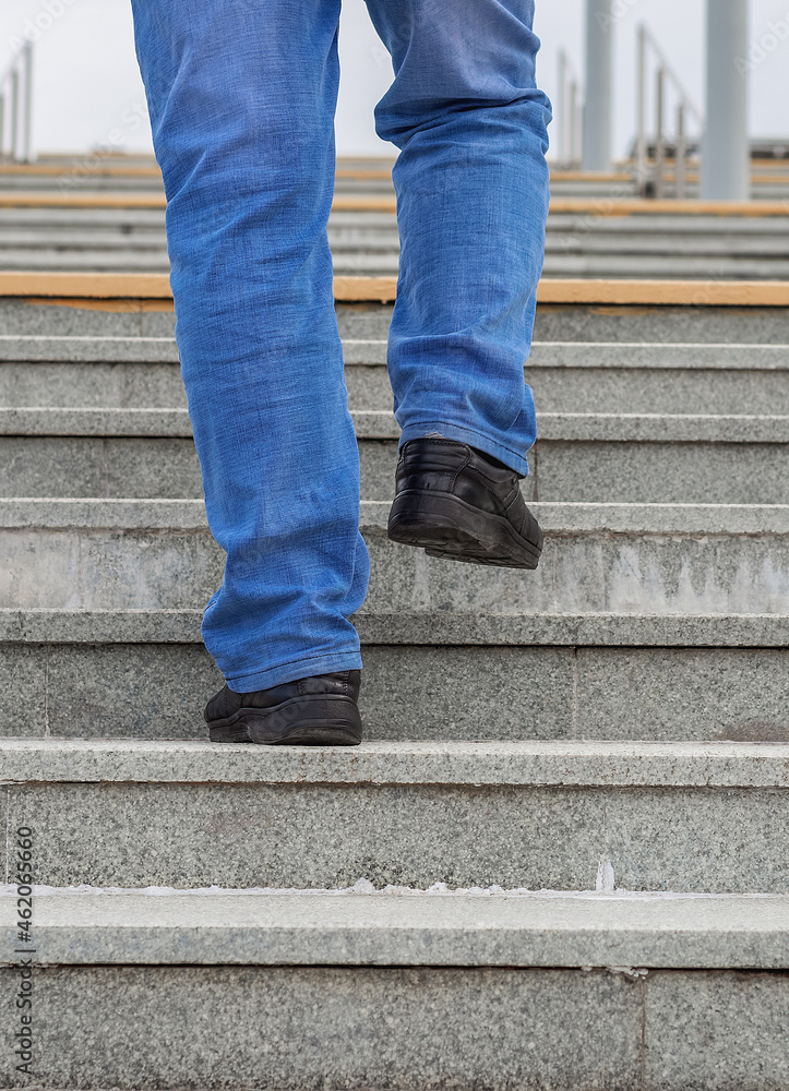 Male legs in jeans and boots climb the stairs. Male legs in jeans and boots climb the stairs.