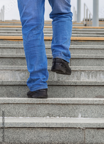 Male legs in jeans and boots climb the stairs.