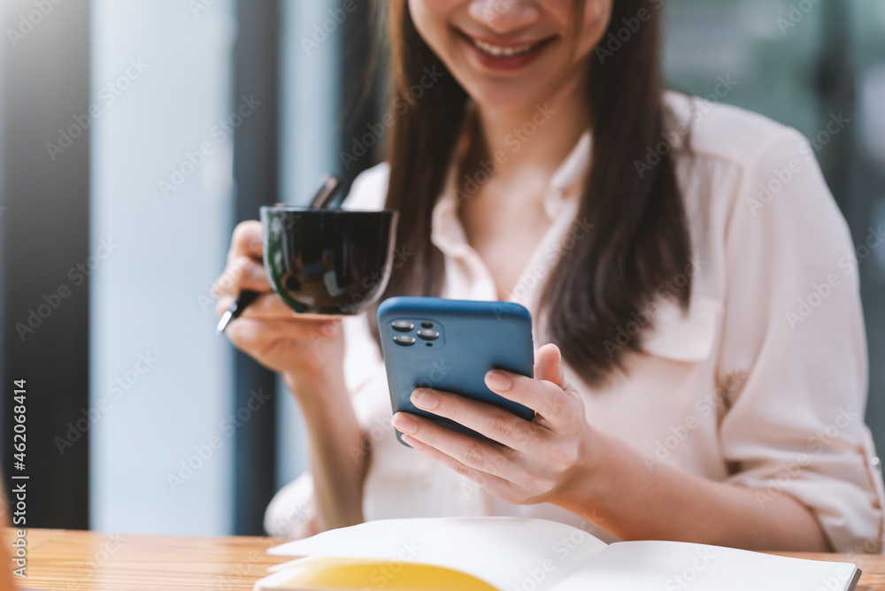 Happy businesswoman relax drink coffee while using your smartphone at the office. Happy businesswoman relax drink coffee while using your smartphone at the office.
