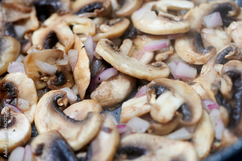 fresh mushrooms frying in a pan with onions