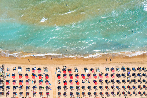 Top view aerial drone photo of Banana beach with beautiful turquoise water, sea waves and red umbrellas. Vacation travel background. Ionian sea, Zakynthos Island, Greece