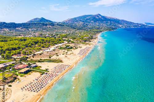 Top view aerial drone photo of Banana beach with beautiful turquoise water, sea waves and red umbrellas. Vacation travel background. Ionian sea, Zakynthos Island, Greece photo