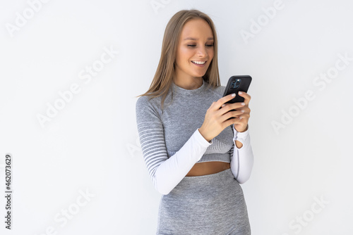 Smiling fitness woman using smartphone on a white background