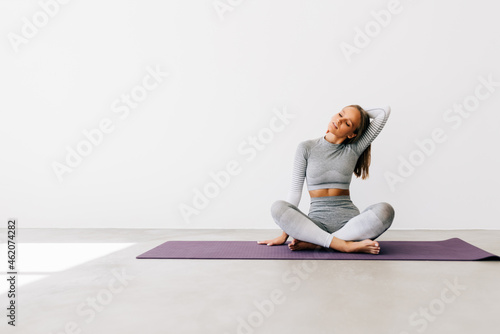 Young female stretching neck while practicing yoga during workout photo