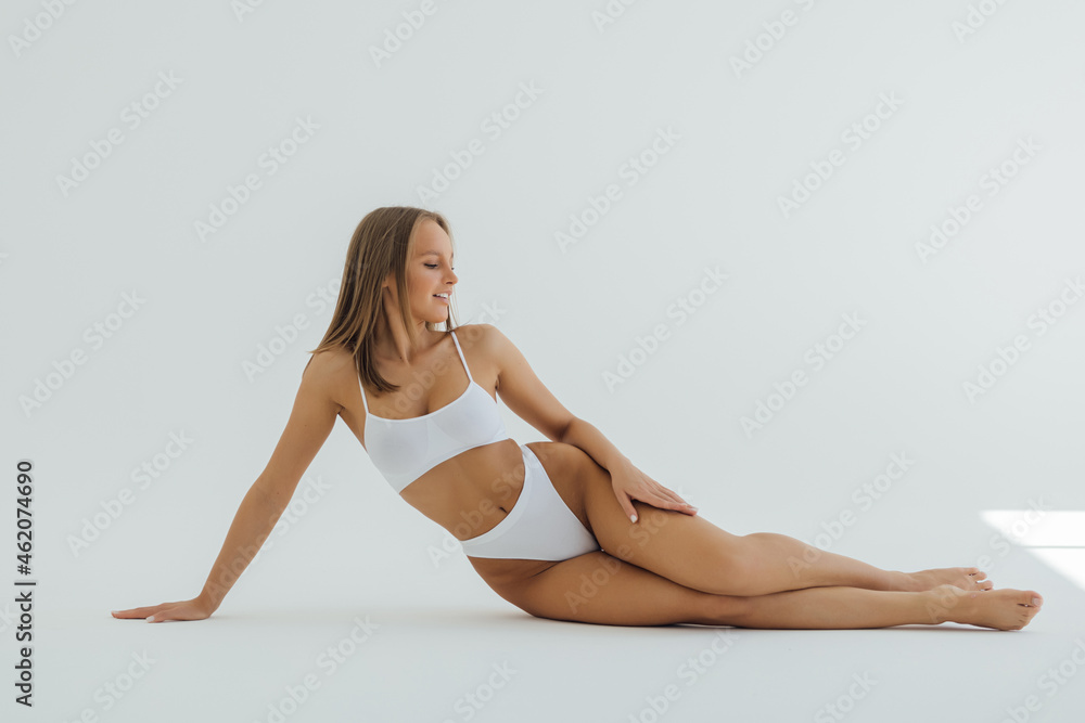 Fit and sporty beautiful woman with perfect shape. Woman in white underwear on the floor. Healthy lifestyle, sport, healthcare, nutrition and diet concept. Fit and sporty beautiful woman with perfect shape. Woman in white underwear on the floor. Healthy lifestyle, sport, healthcare, nutrition and diet concept.