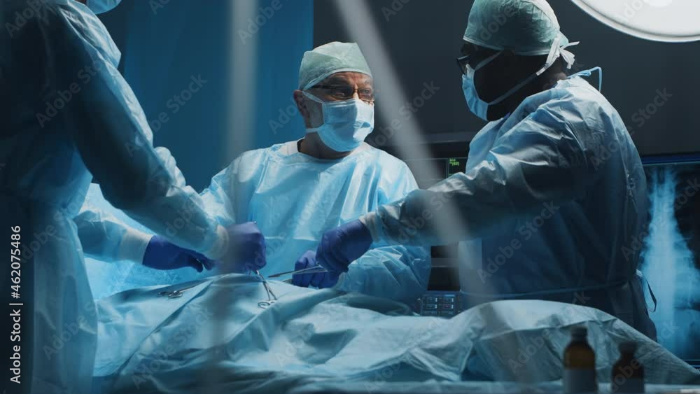 Multiracial team of professional medical surgeons performs the surgical operation in a modern hospital. Doctors are working to save the patient. Medicine, health, cardiology and transplantation. Multiracial team of professional medical surgeons performs the surgical operation in a modern hospital. Doctors are working to save the patient. Medicine, health, cardiology and transplantation.