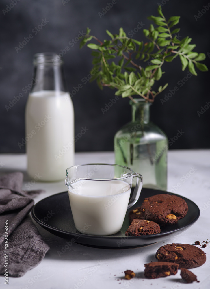 Plate with Chocolate cookies with nuts and glass of milk on dark background. Nordic style. Plate with Chocolate cookies with nuts and glass of milk on dark background. Nordic style.