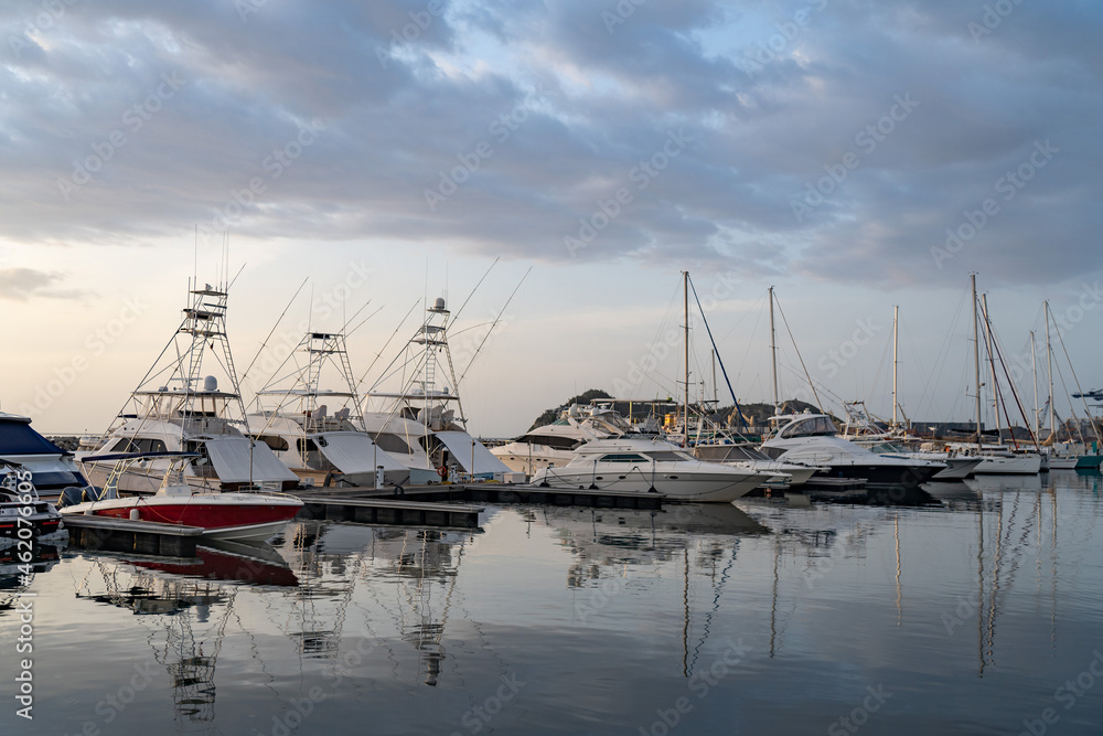 Many motorboats and sailboats Docked at a Marina on dramatic sunrise background Many motorboats and sailboats Docked at a Marina on dramatic sunrise background