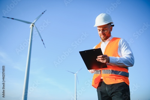 Electrical engineers working at wind turbine power generator station with laptop computer