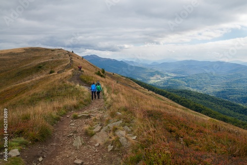 Fototapeta Naklejka Na Ścianę i Meble -  Bieszczady jesienią. Turyści na górskich szlakach. Połoniny. Ciemne chmury. Korory jesieni.