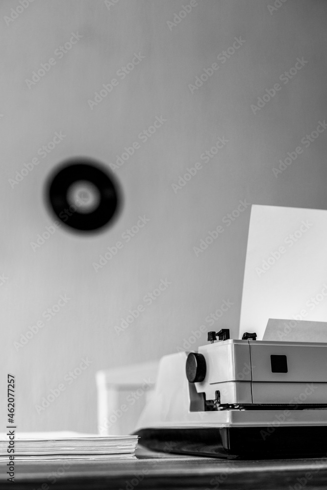 Stack of paper and vintage old typewriter at wooden desk table.