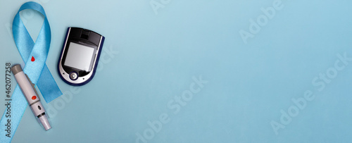 Close up top view of concept for World Diabetes Day 14 November. Blue tape with blood drops and a glucometer on a blue background