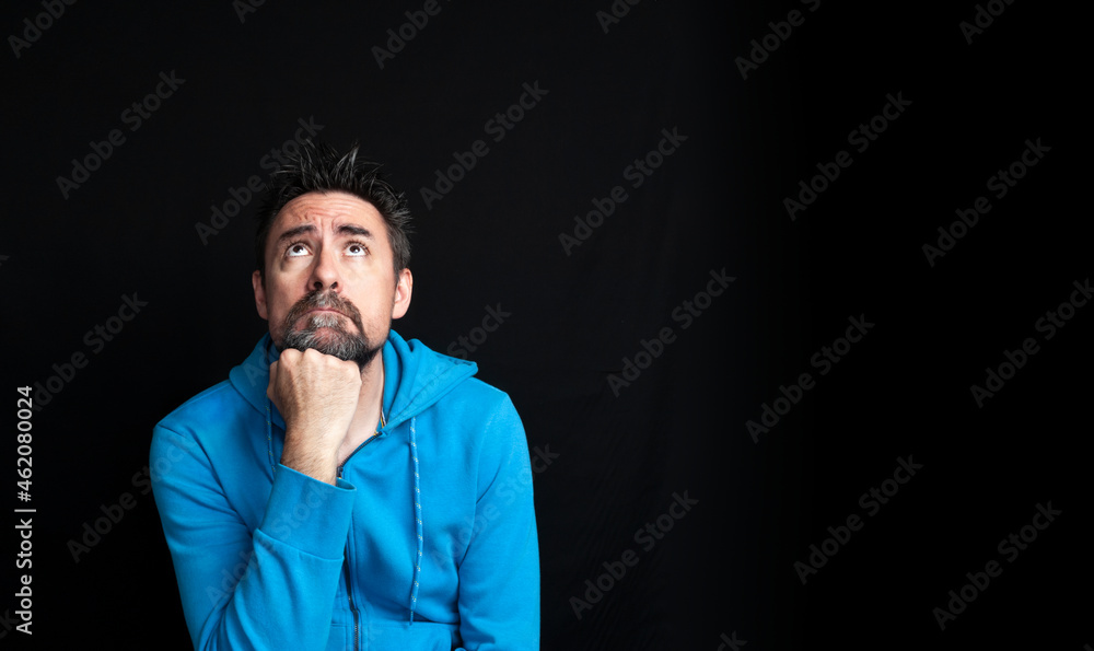 Young man looking up with his fist resting on his chin in a dreamy or pensive attitude. Young man looking up with his fist resting on his chin in a dreamy or pensive attitude.