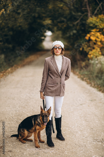 Beautiful woman walking out her dog in autumn park