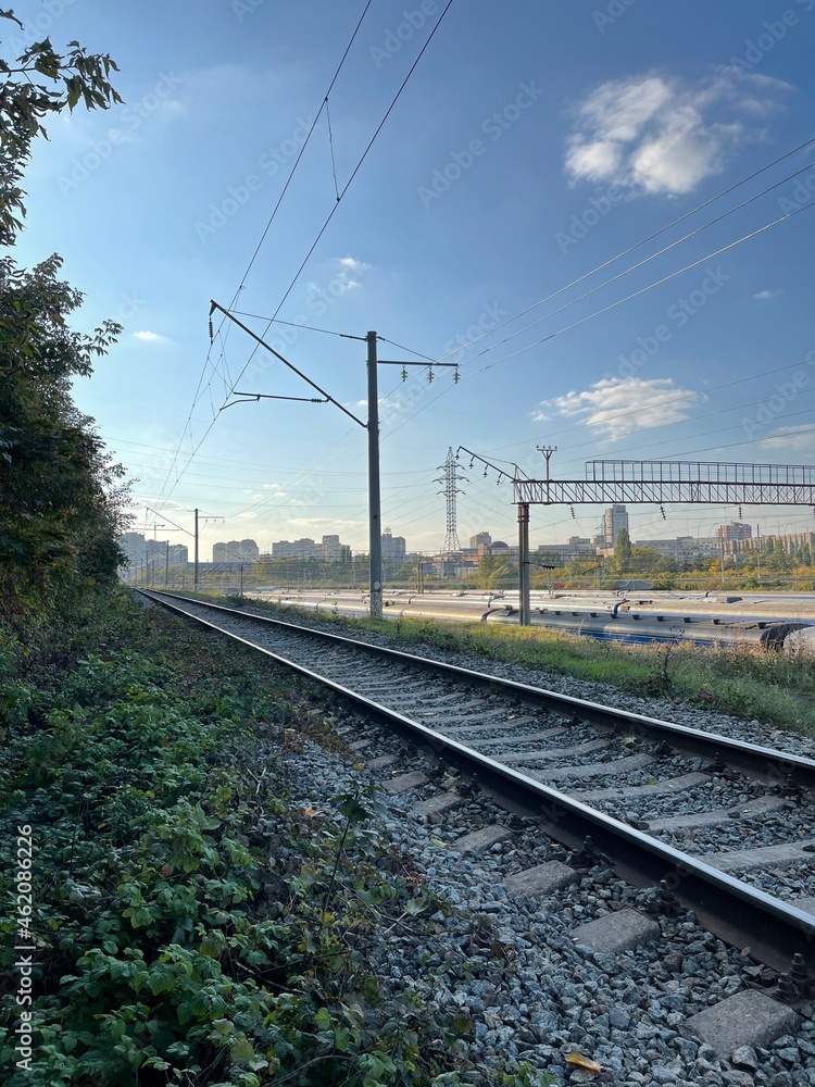Vertical shot of railway under blue autumn sky passing near forest