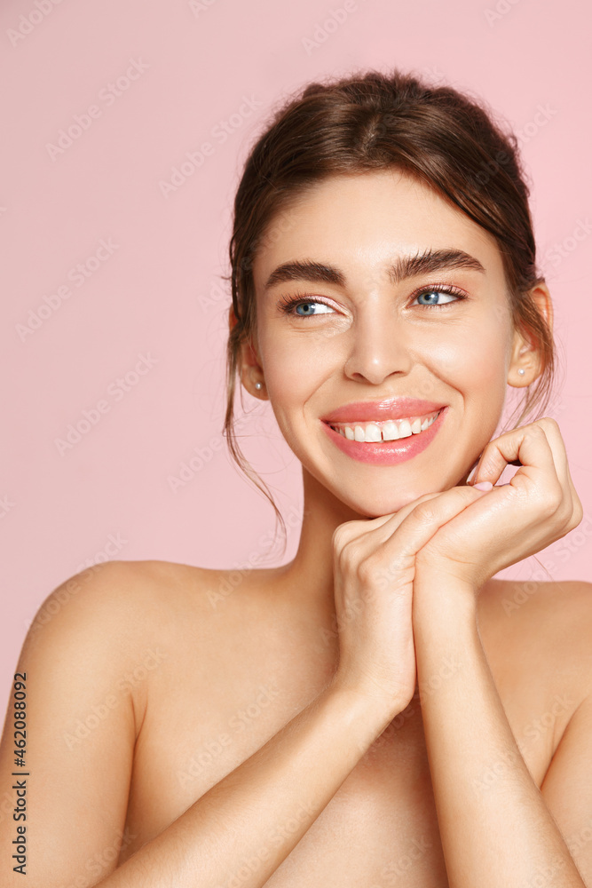 Vertical portrait of beautiful natural girl, white smile and happy face, holding hands near nourished, clean skin, showering and cleansing skin, pink background Vertical portrait of beautiful natural girl, white smile and happy face, holding hands near nourished, clean skin, showering and cleansing skin, pink background