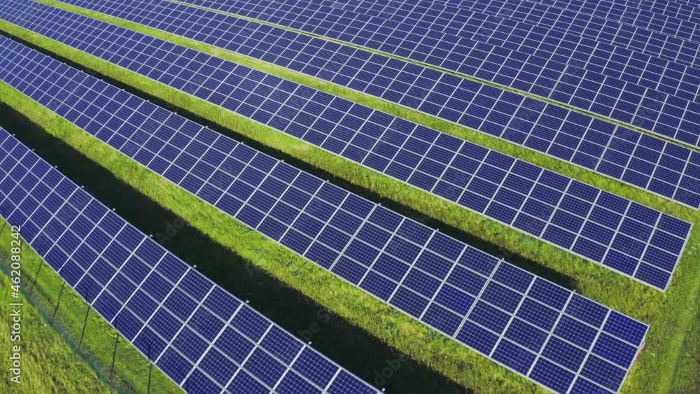 Solar panels in aerial view. Solar power electric station in green grass field at sunny day. Solar panels in aerial view. Solar power electric station in green grass field at sunny day.