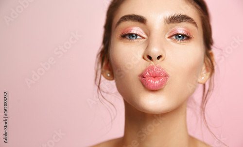 Cosmetics and skin care. Portrait of beautiful woman pucker lips, kissing, showing natural clean facial skin, standing over pink background