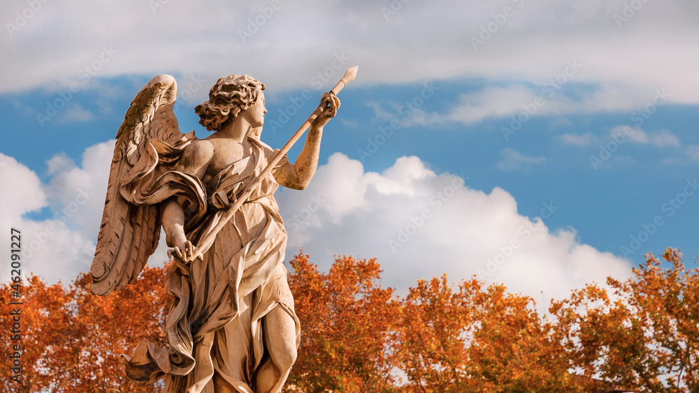 Autumn in Rome. Beautiful angel statue with Holy Lance of Longinus at the top of Sant'Angelo Bridge, erected in the 17th century, with atumnal leaves in the background Autumn in Rome. Beautiful angel statue with Holy Lance of Longinus at the top of Sant'Angelo Bridge, erected in the 17th century, with atumnal leaves in the background