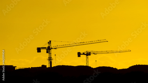 Construction industry and development. Crane at work against golden sunset sky