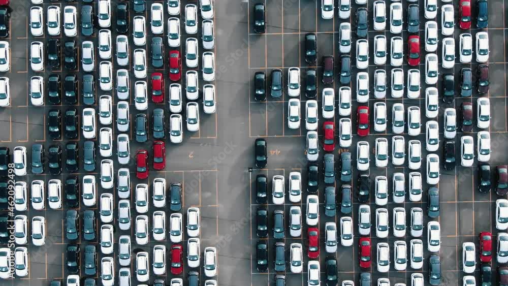 Parallel rows of finished cars of different colours at open warehouse ground of giant plant in early summer morning aerial view Parallel rows of finished cars of different colours at open warehouse ground of giant plant in early summer morning aerial view