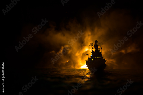 Silhouettes of a crowd standing at blurred military war ship on foggy background. Selective focus.