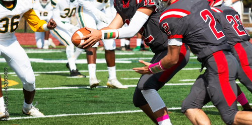 Football quarterback handing off the ball during a game photo