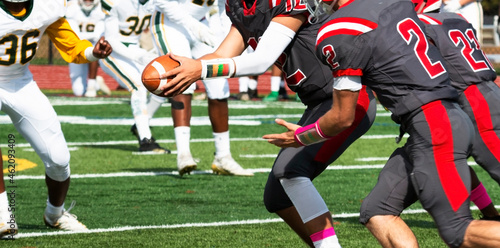 Football quarterback handing off the ball during a game