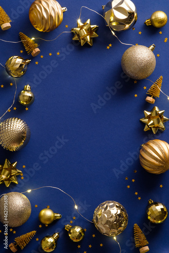Christmas vertical banner design. Frame made of golden Christmas decorations, balls, tinsel on dark blue background. Xmas frame.