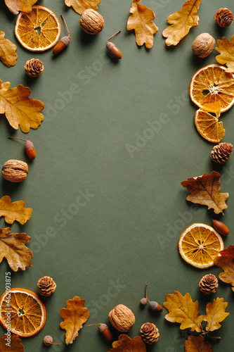 Frame made of oranges, dry oak leaves, nuts, acorns on vintgae green background. Autumn fall, Thanksgiving concept.