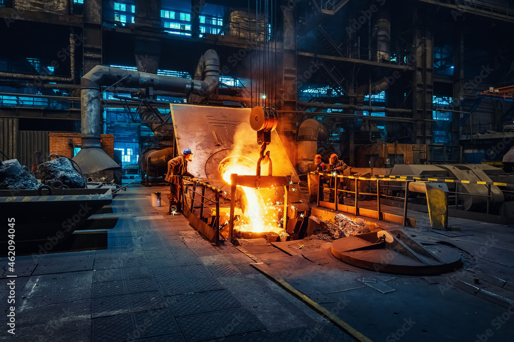 Metal cast process in blast furnace in metallurgical plant or factory. Liquid iron molten metal pouring in container, heavy industry background. - obrazy, fototapety, plakaty 