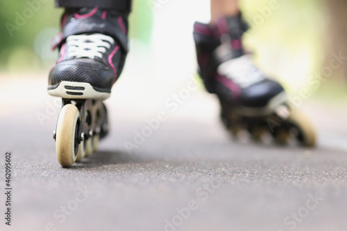 Woman is rolling on black beautiful rollerblades on asphalt closeup photo