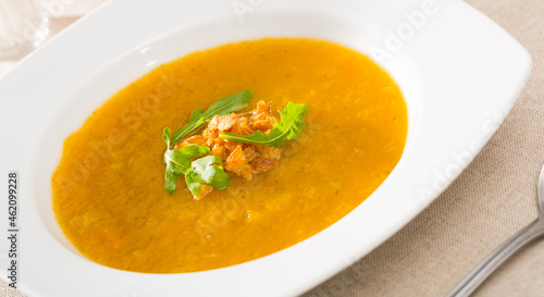 Vegetarian concept. Vegetable soup puree served in white plate with fresh greens ..